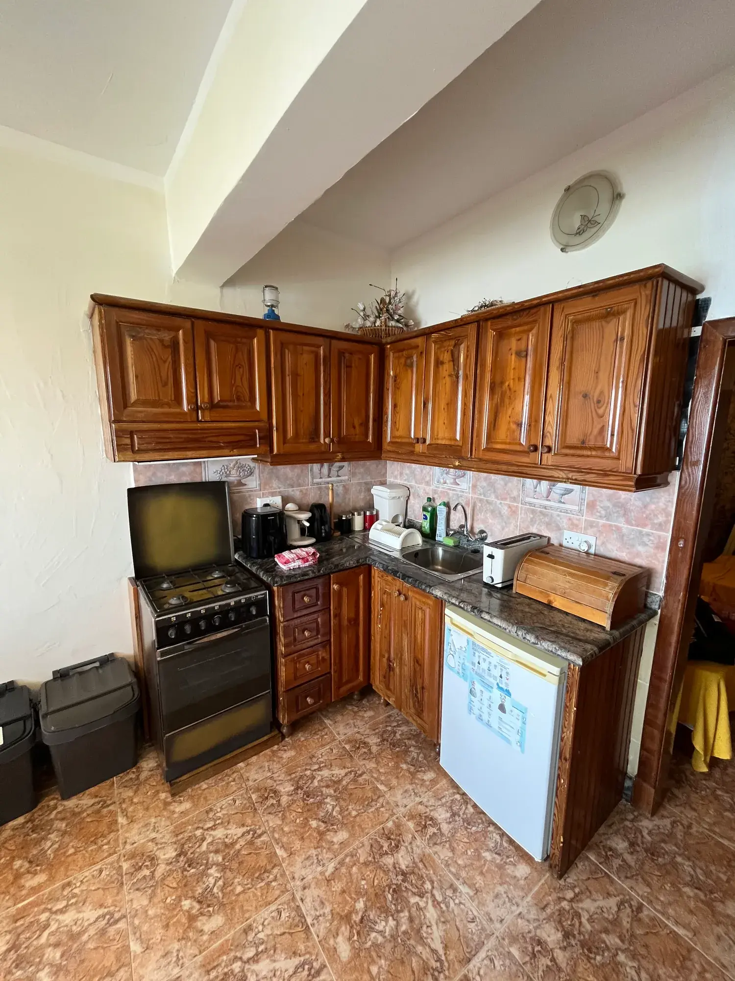 Wooden kitchen cabinets, cooker and fridge at Sultana Apartment 8
