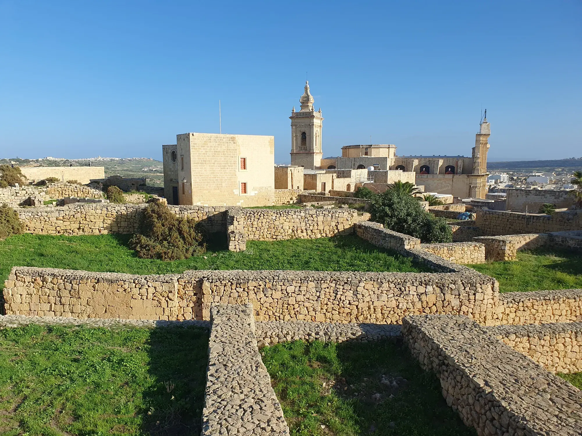 Limestone walls and cathedral towers inside Gozo’s Citadel under a blue sky