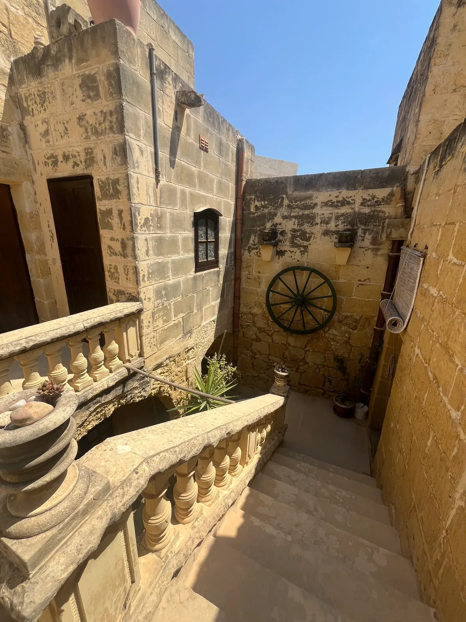 Sunlit limestone courtyard and carved stone balcony at Casa Barone